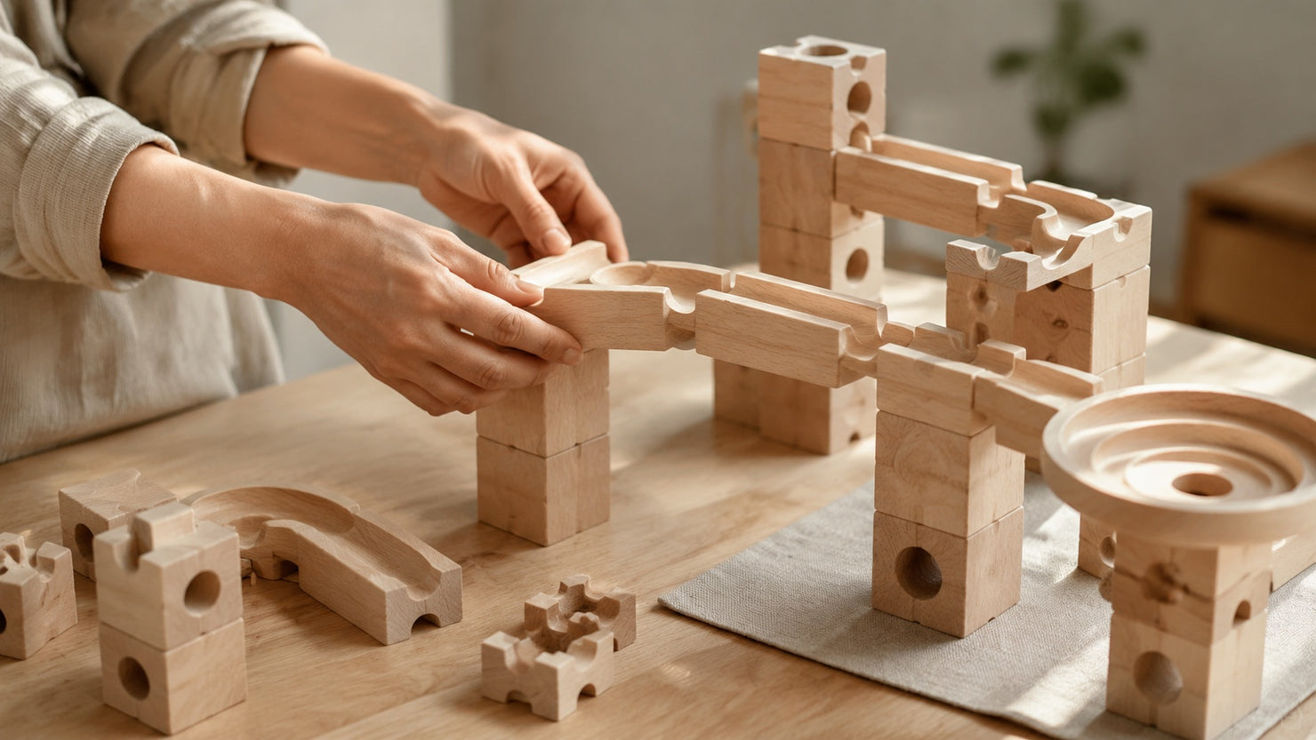 Assembling a Jigden wooden marble run kit on a clean, sunlit desk