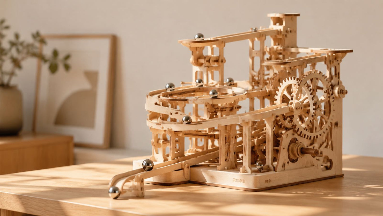 A complex 3D wooden marble run kit in motion on a clean desk, showcasing kinetic movement and precision laser-cut birch wood.