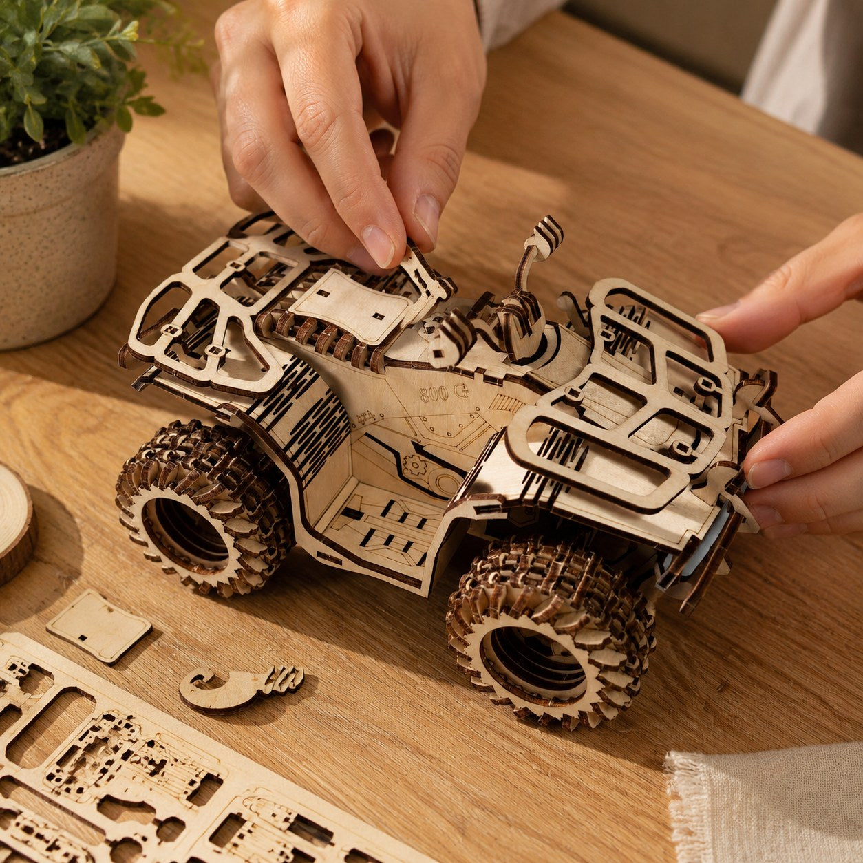 Hands assembling the wooden ATV puzzle on a workbench.