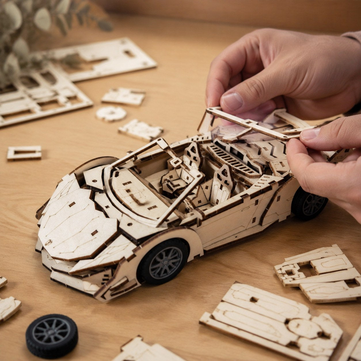 Person assembling the 3D wooden supercar puzzle on a workbench