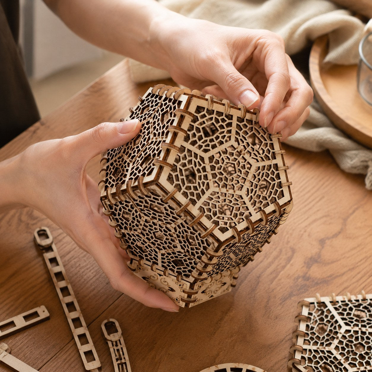 Person assembling the wooden geometric lantern puzzle