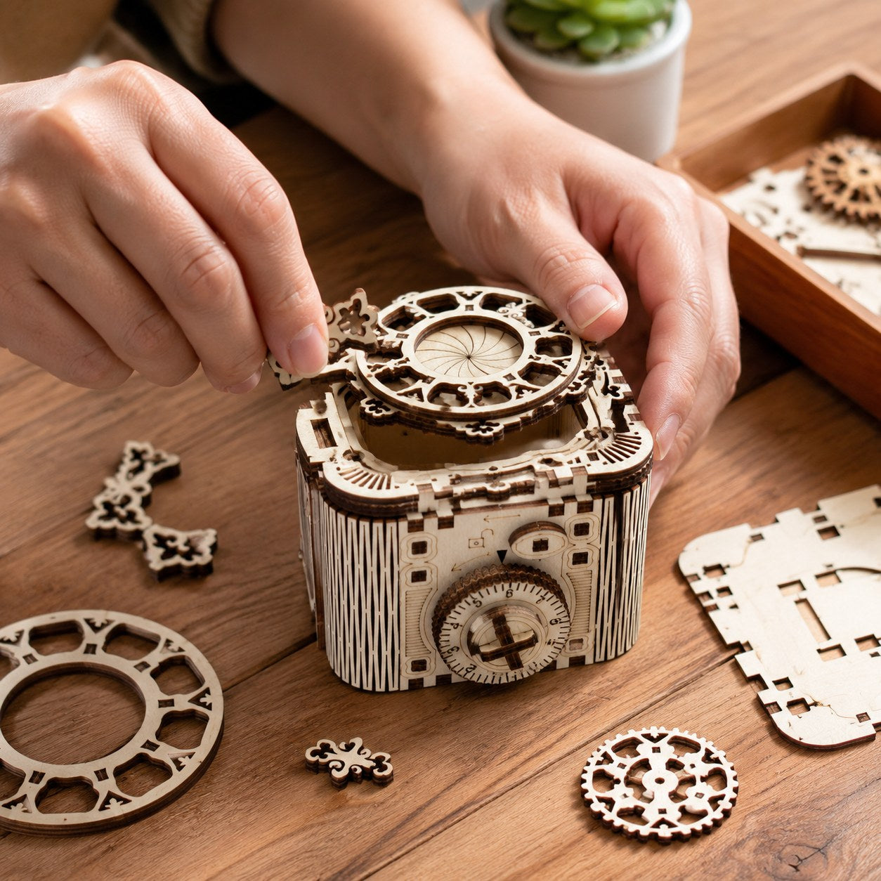 Adult hands assembling the wooden mechanical cipher box on a workbench