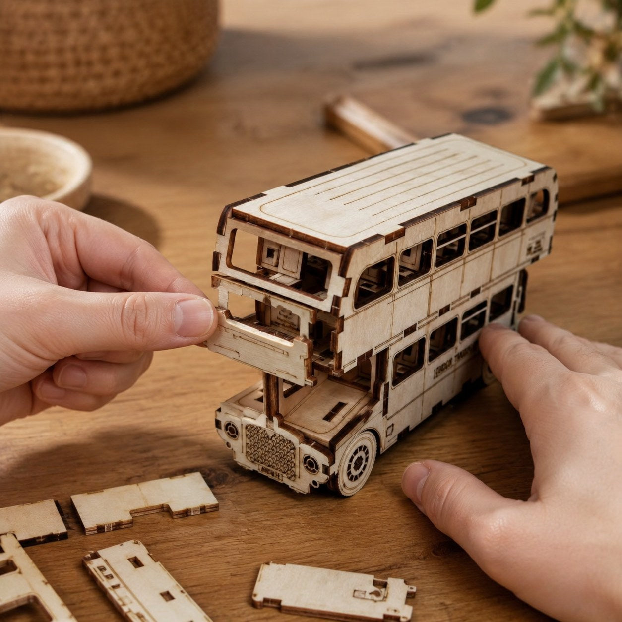 Adult hands assembling the wooden double-decker bus model