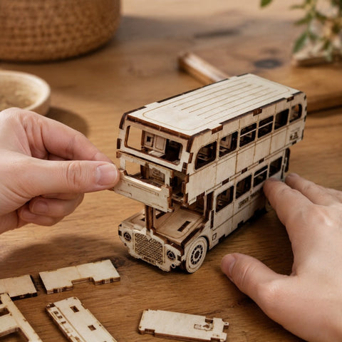 Adult hands assembling the wooden double-decker bus model