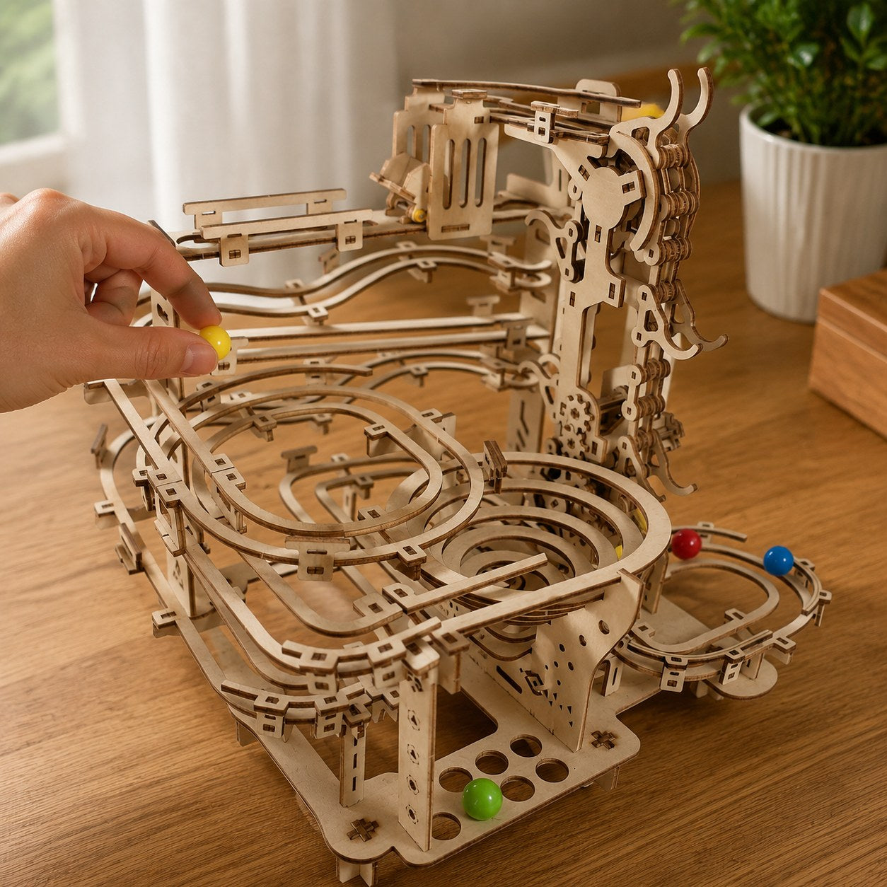 Adult hand placing a marble on the mechanical marble run 3D wooden puzzle to show scale.