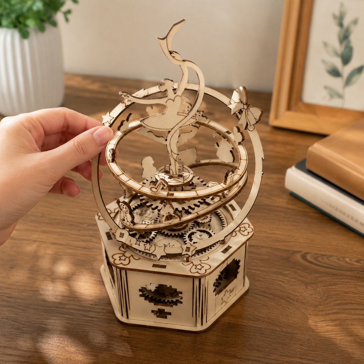 Adult hand next to the assembled Jigden wooden music box showing scale and dimensions