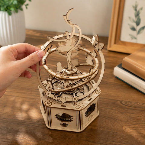 Adult hand next to the assembled Jigden wooden music box showing scale and dimensions