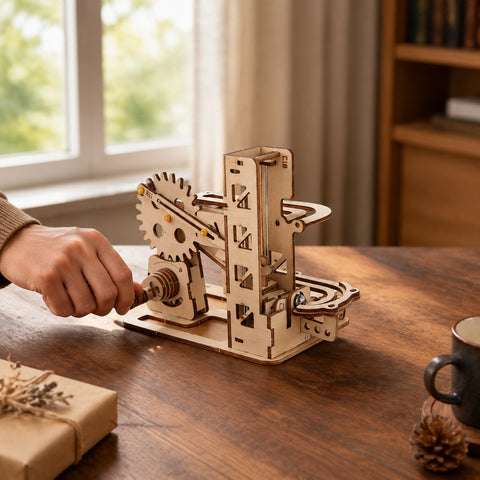Hand turning the crank of the compact wooden marble run
