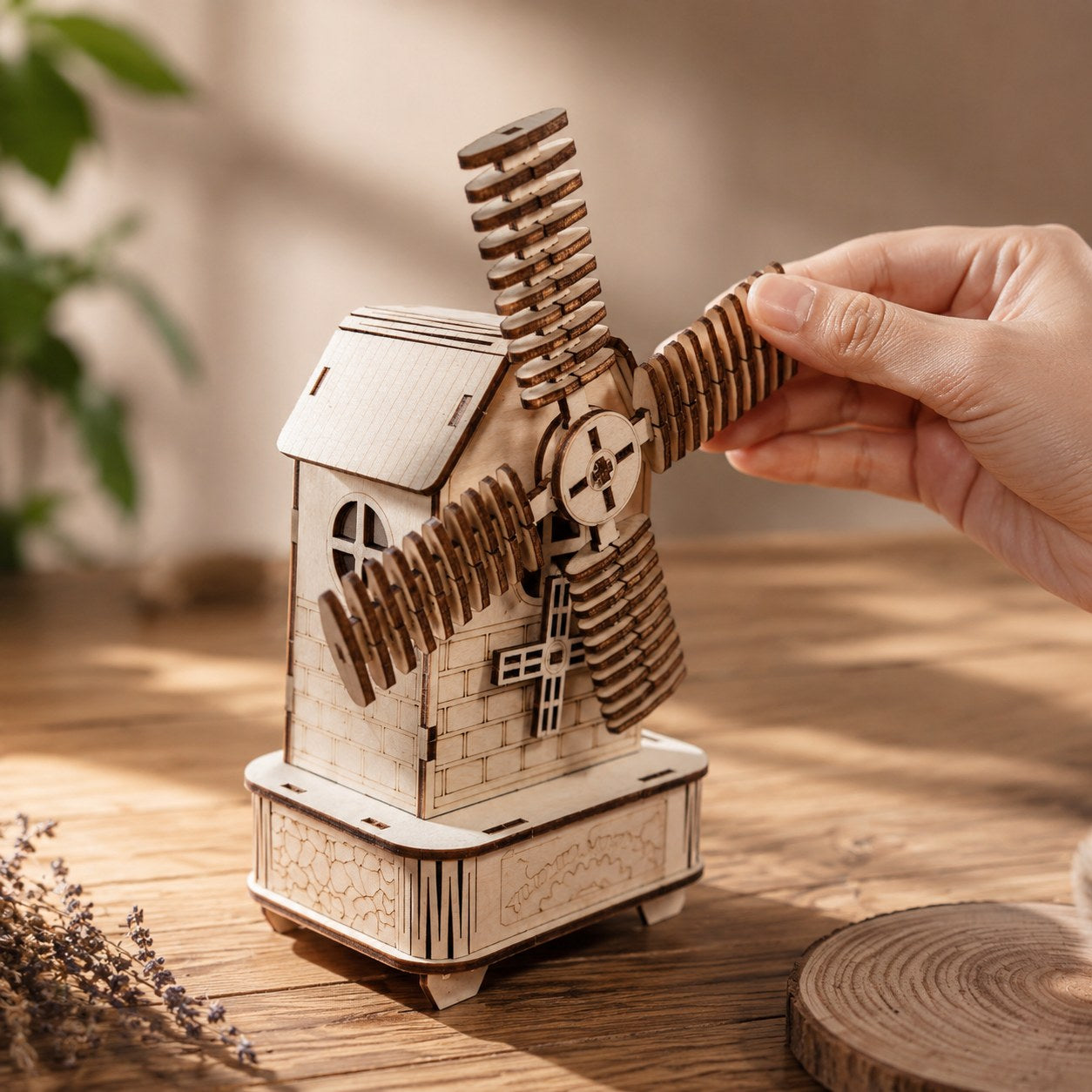 Hand turning the sail of the completed wooden windmill music box to show scale