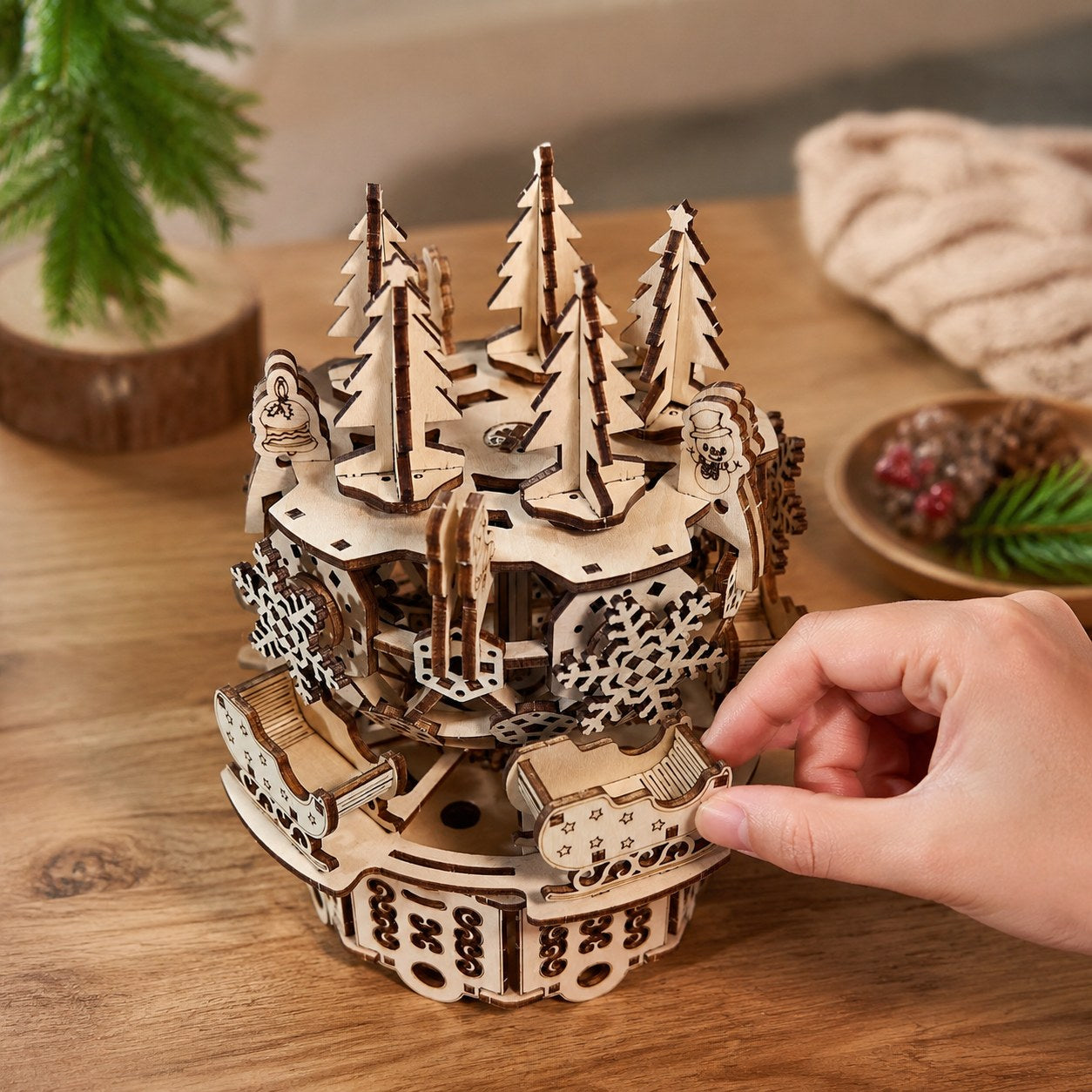 Hand adjusting the wooden Christmas carousel showing scale
