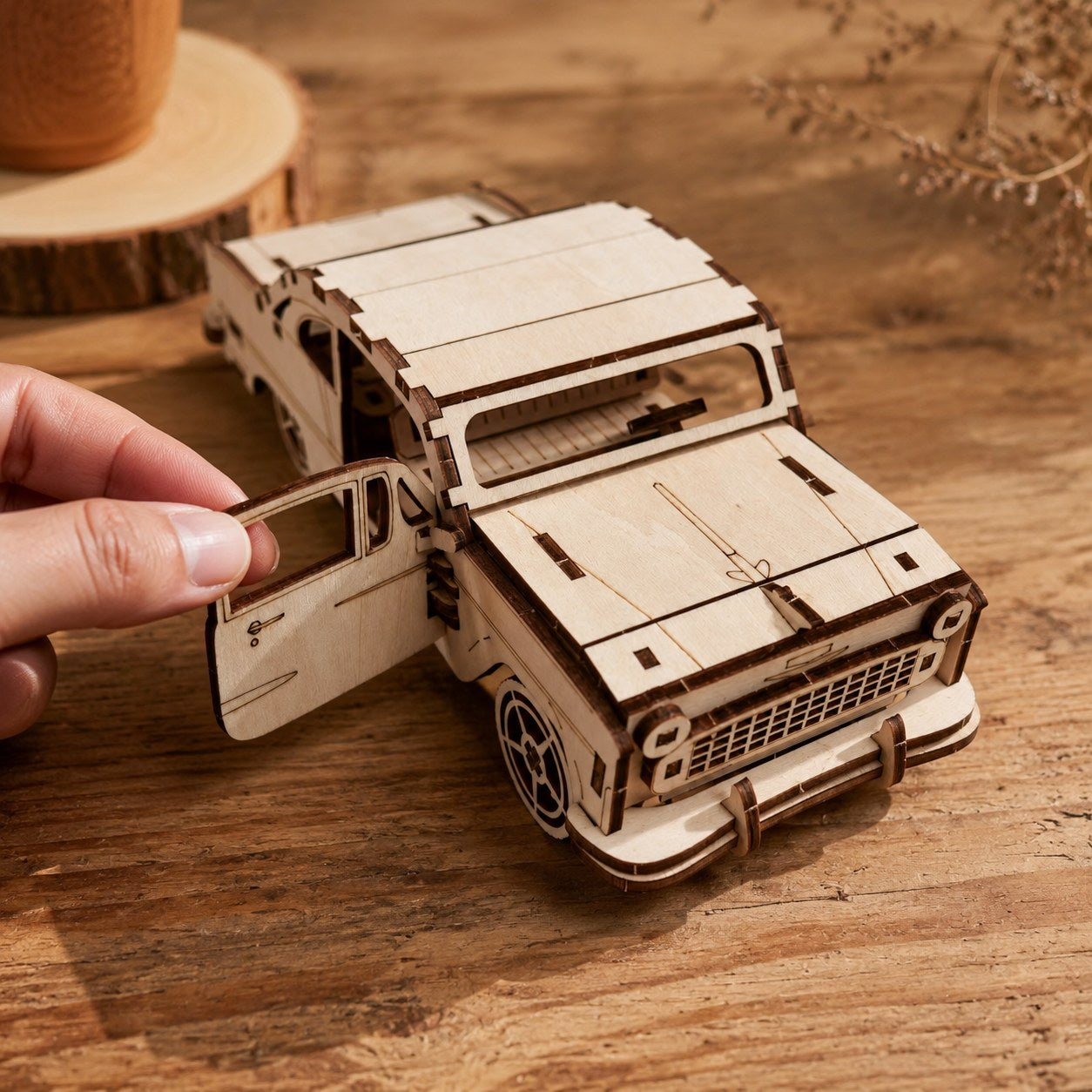Hand opening the door of the Vintage Sedan wooden model to show scale