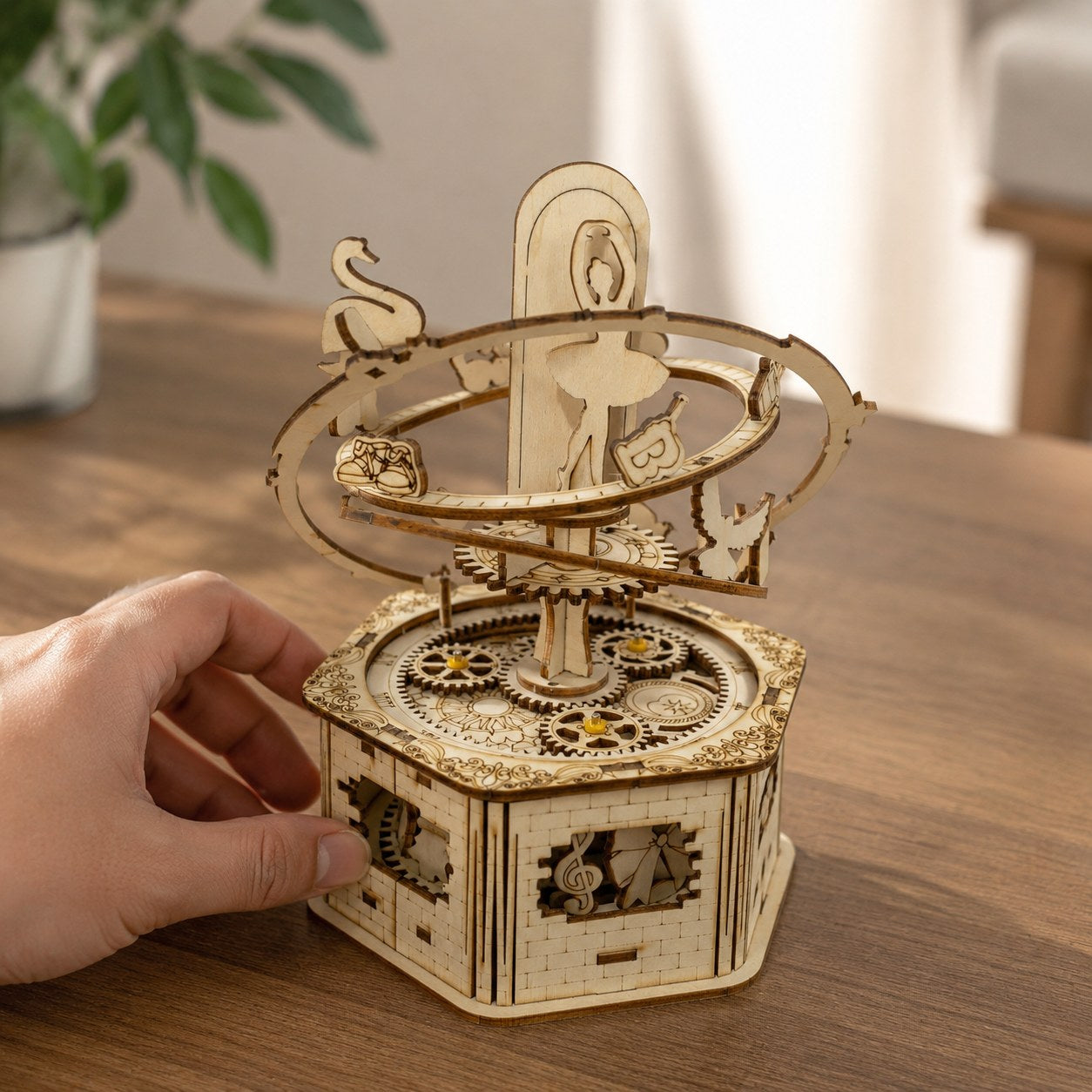 Hand turning the gears of the assembled wooden ballerina music box for scale