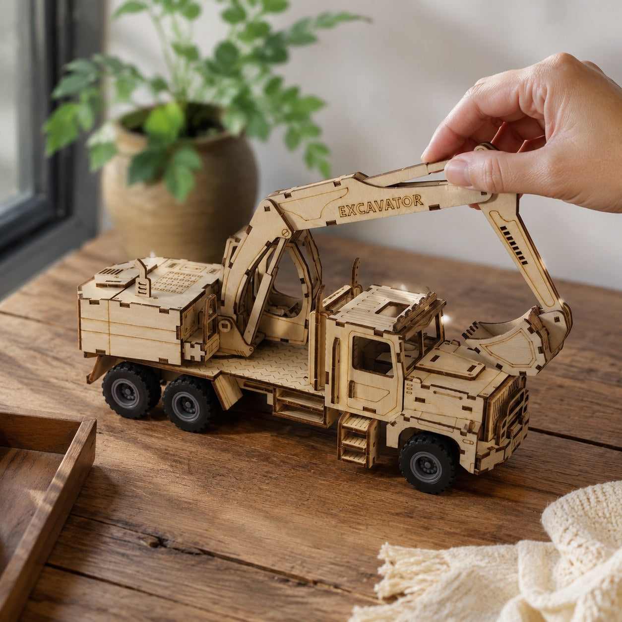 Hand adjusting the wooden excavator model showing scale