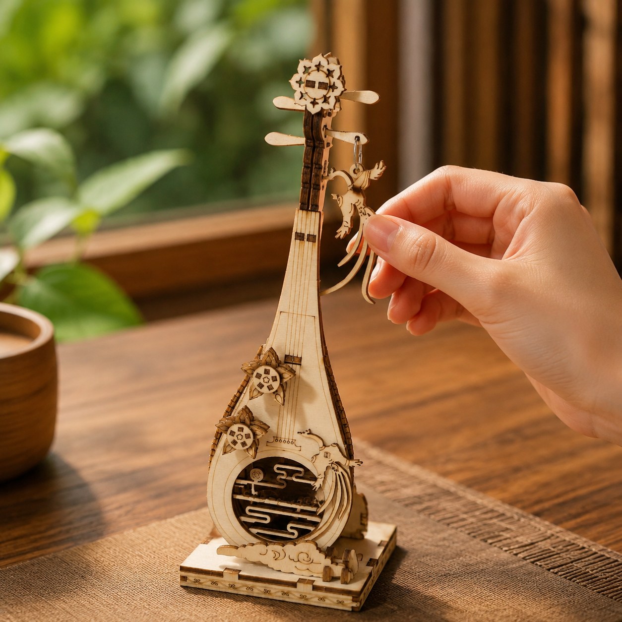 Adult hand adjusting the wooden phoenix charm on the finished Pipa model to show scale
