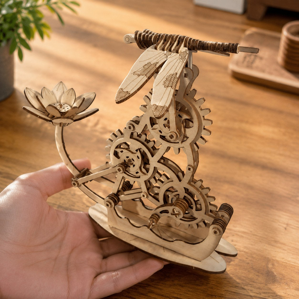 Adult hand holding the assembled hovering dragonfly 3D wooden puzzle
