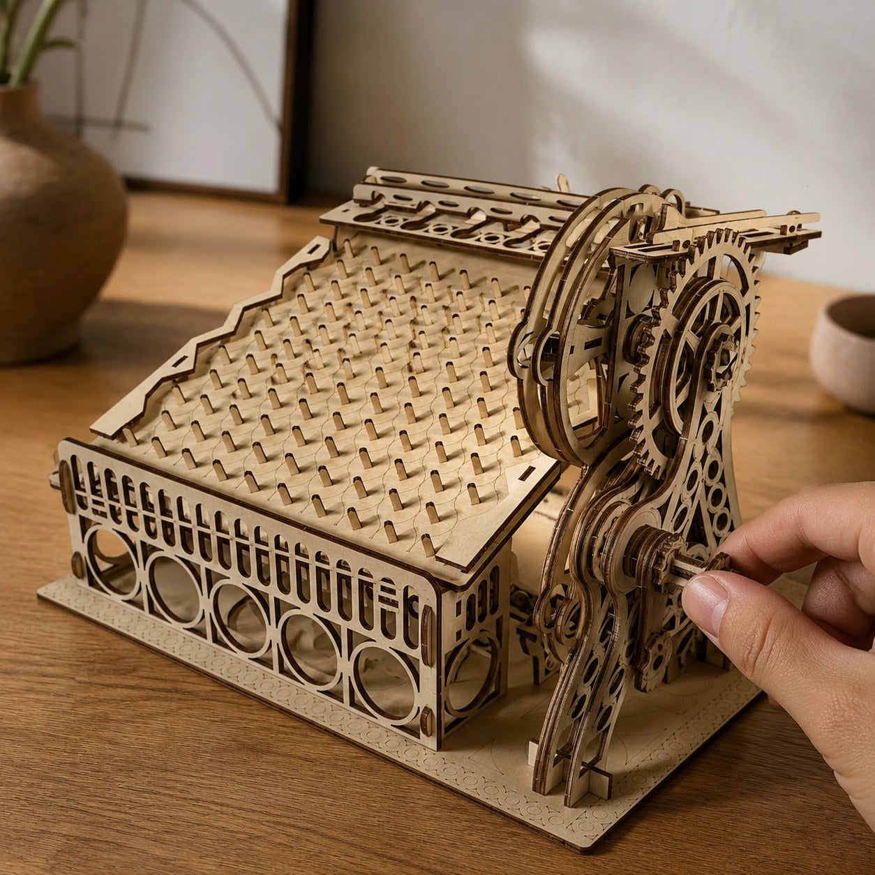 Hand turning the crank on the wooden peg maze model