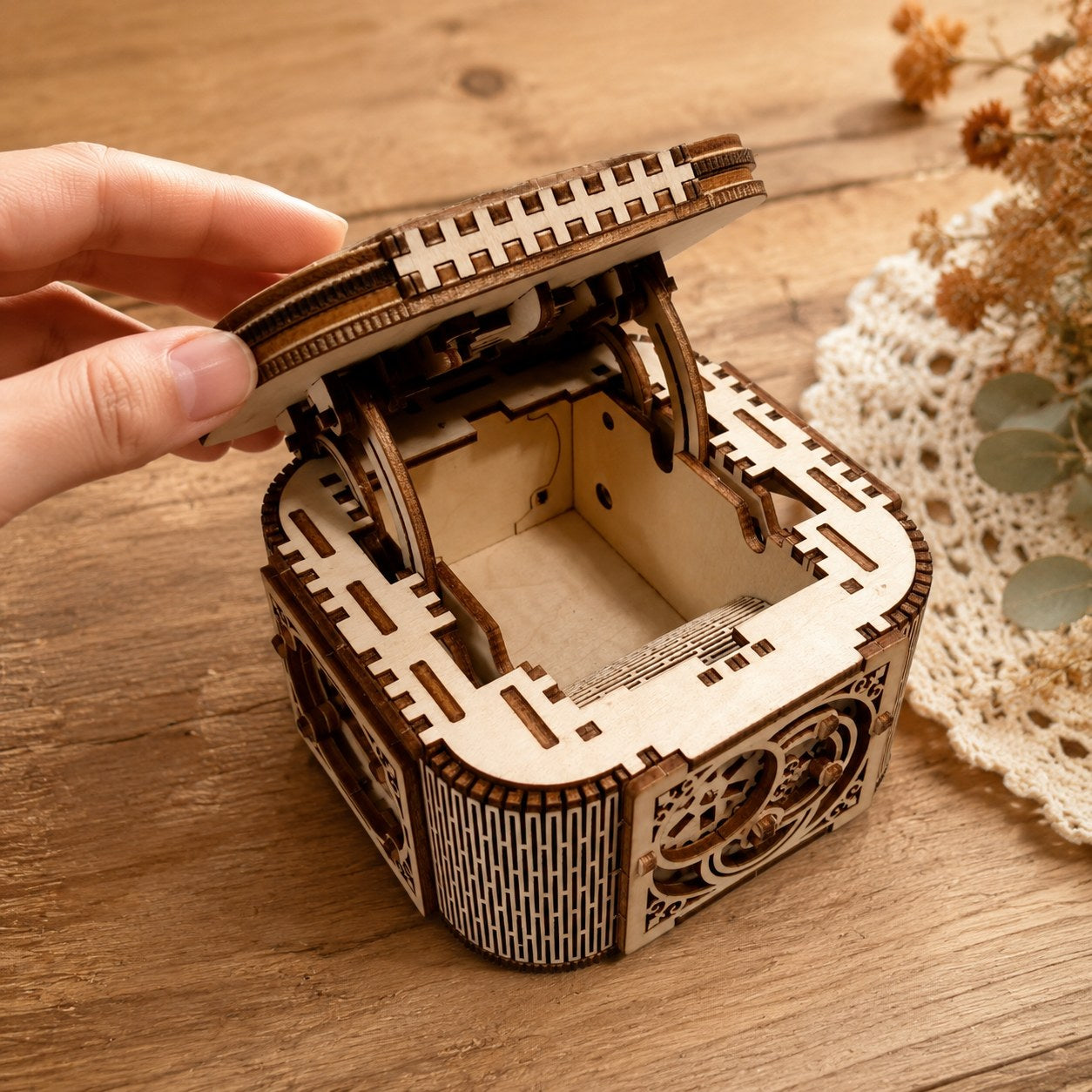 Hand opening the cantilever lid of the wooden jewelry box to show scale