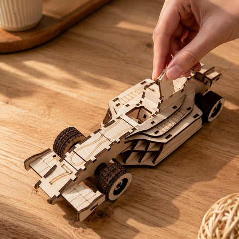 Hand adjusting a wooden race car model showing scale