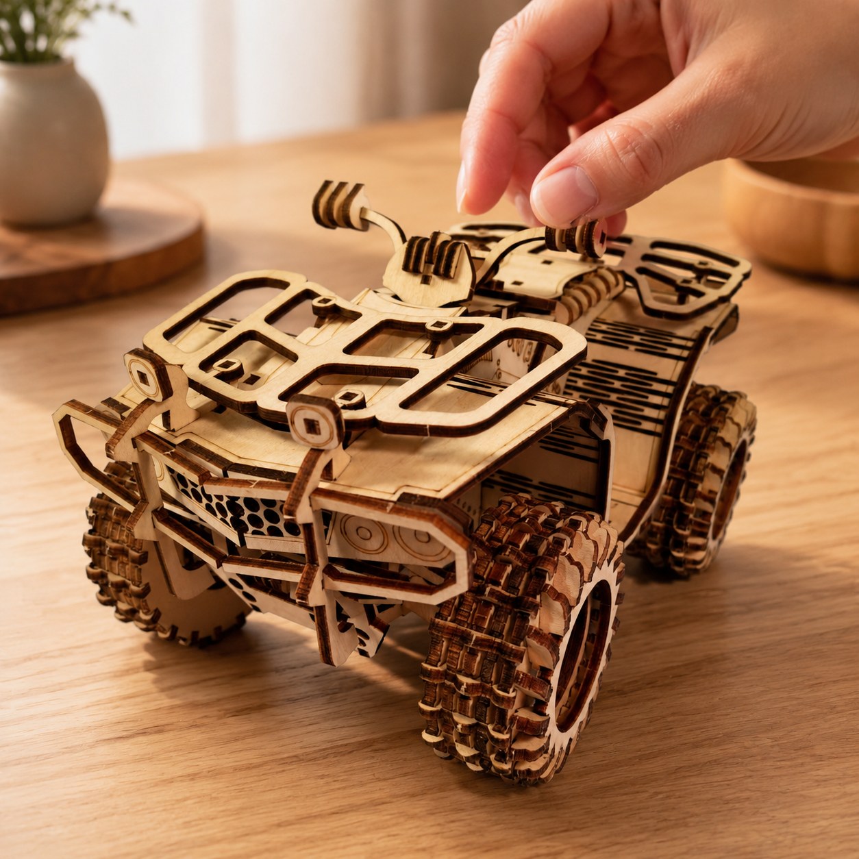 Adult hand next to the finished wooden ATV model for scale.