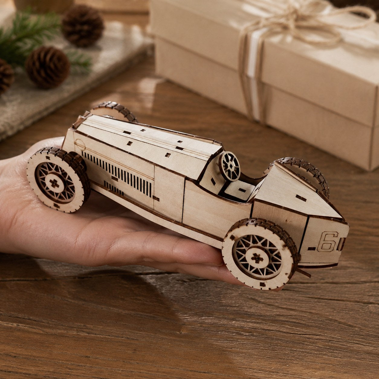 Adult hand holding the assembled wooden race car model to show scale