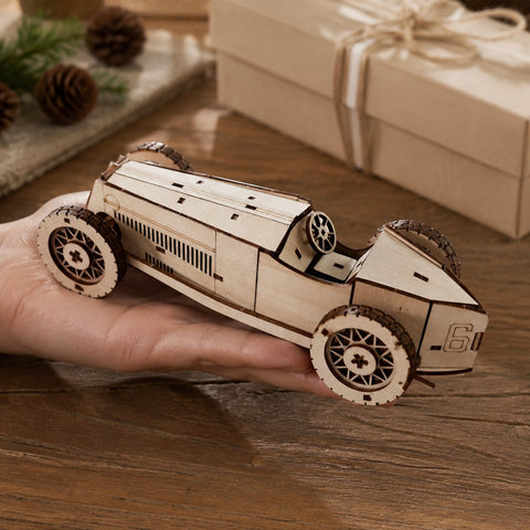Adult hand holding the assembled wooden race car model to show scale