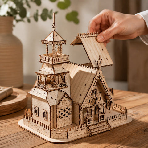 Hand placing a piece on the finished wooden manor puzzle for scale