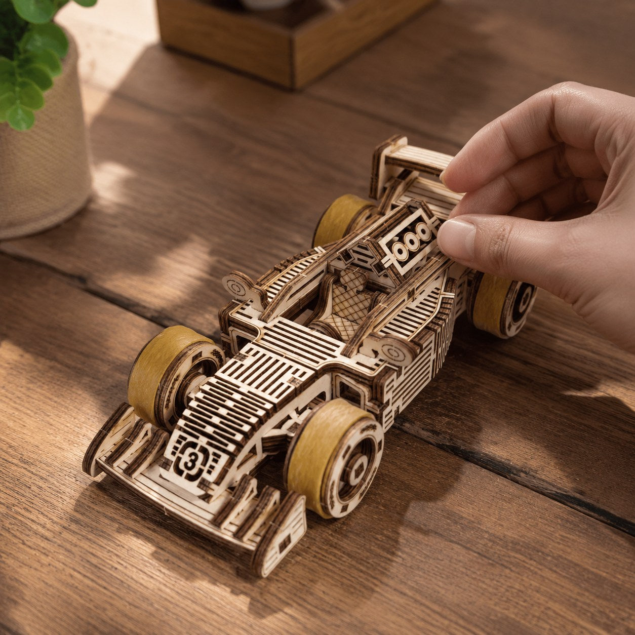 Hand adjusting the finished wooden race car model showing scale