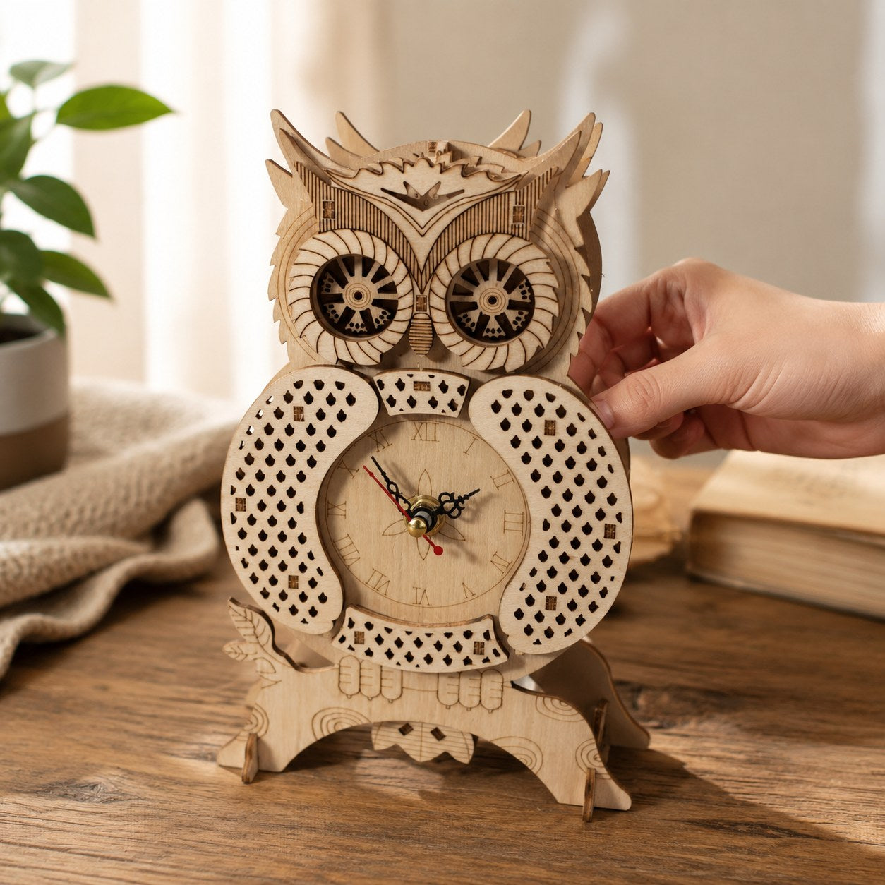 Hand touching the assembled owl clock to show scale