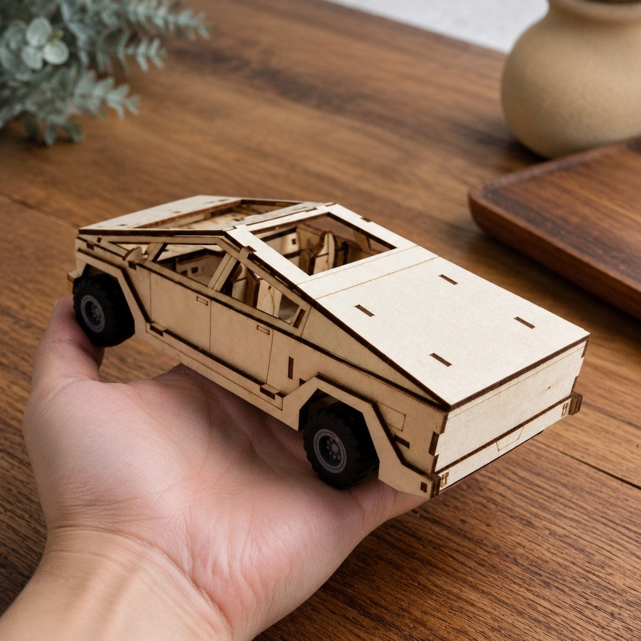 Adult hand holding the finished wooden cyber-style truck model for scale