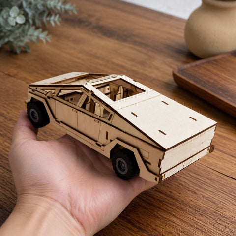Adult hand holding the finished wooden cyber-style truck model for scale