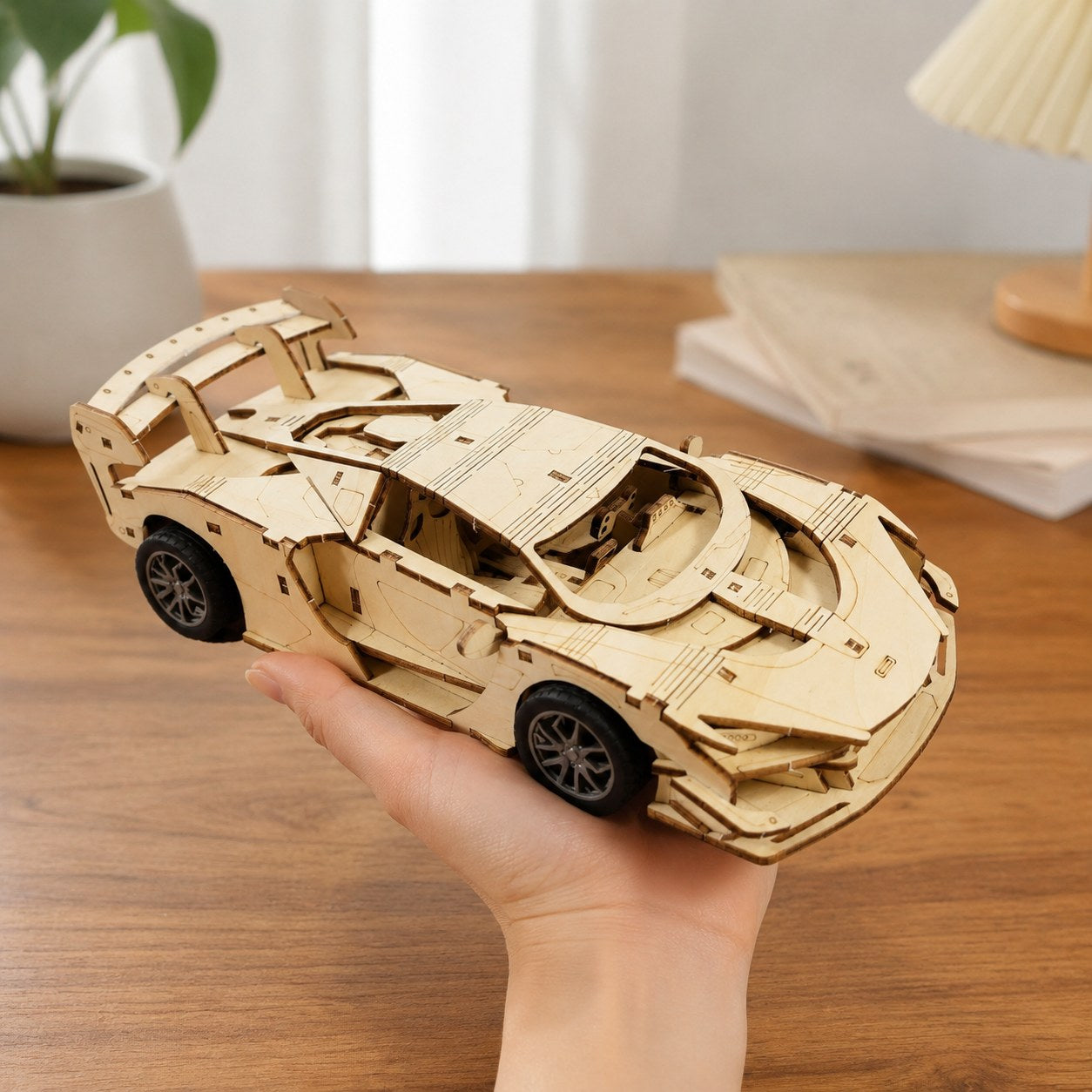 Adult hand holding the finished wooden supercar model for scale