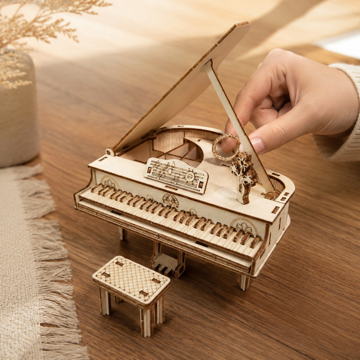 Adult hand placing a ring into the secret storage compartment of the wooden piano model