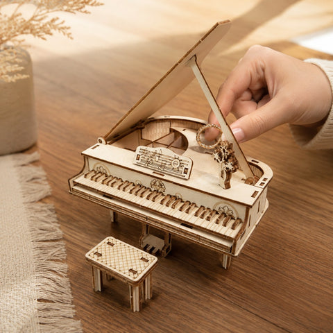 Adult hand placing a ring into the secret storage compartment of the wooden piano model