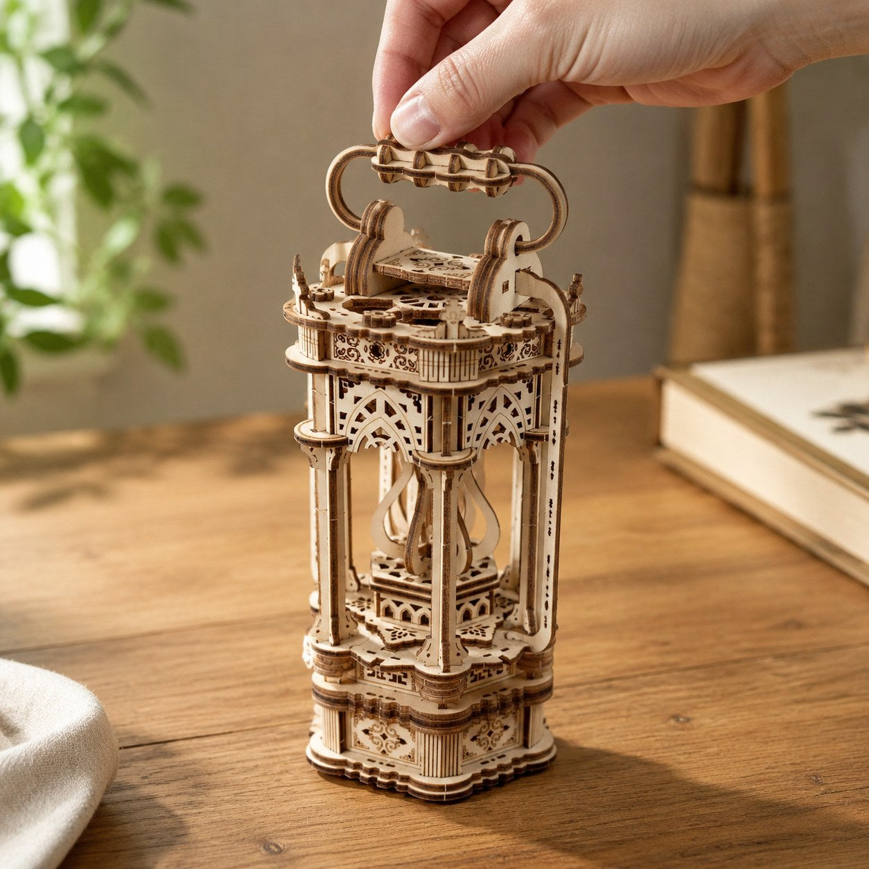 Adult hand holding the decorative carrying handle of the finished Tang lantern puzzle for scale.
