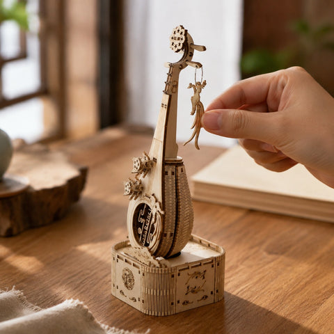 Adult hand adjusting the phoenix charm on the finished wooden Pipa model for scale