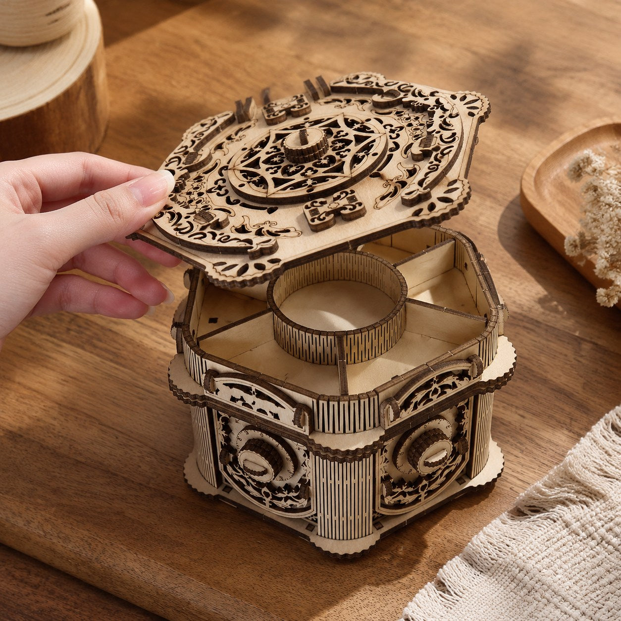 Hand opening the lid of the wooden jewelry box to show scale