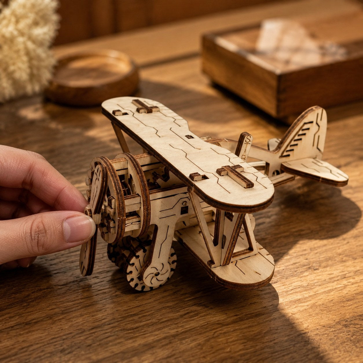 Adult hand touching the propeller of the finished wooden biplane to show scale