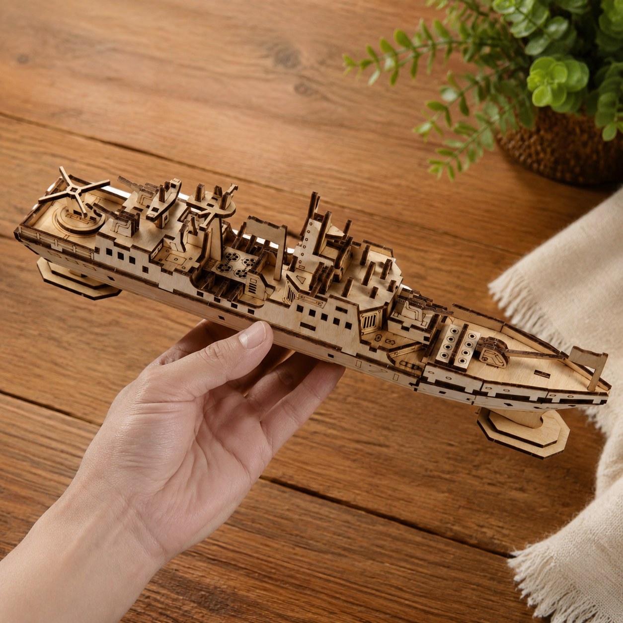Adult hand holding the finished wooden warship model to show its size