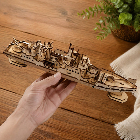 Adult hand holding the finished wooden warship model to show its size