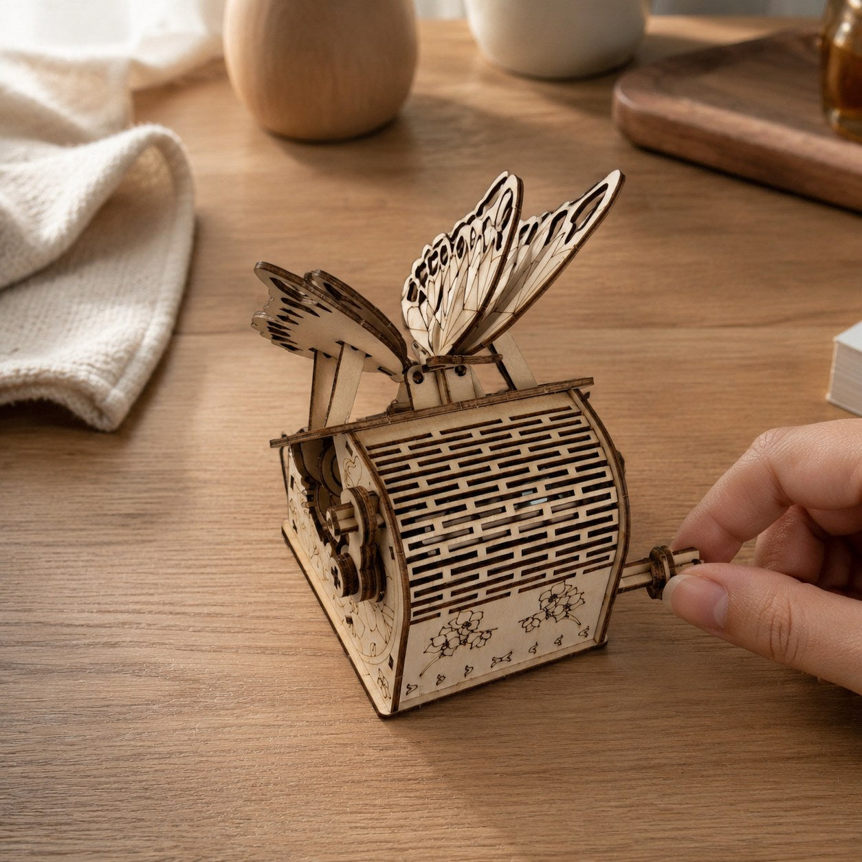 Hand turning the crank of the wooden butterfly puzzle.