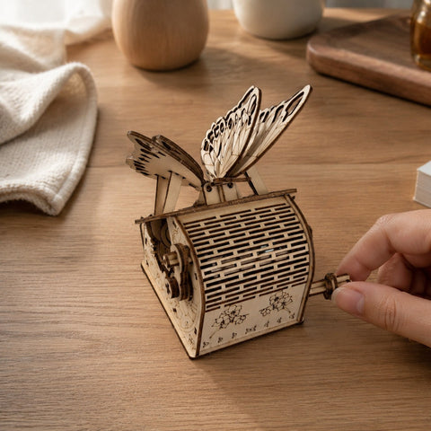 Hand turning the crank of the wooden butterfly puzzle.