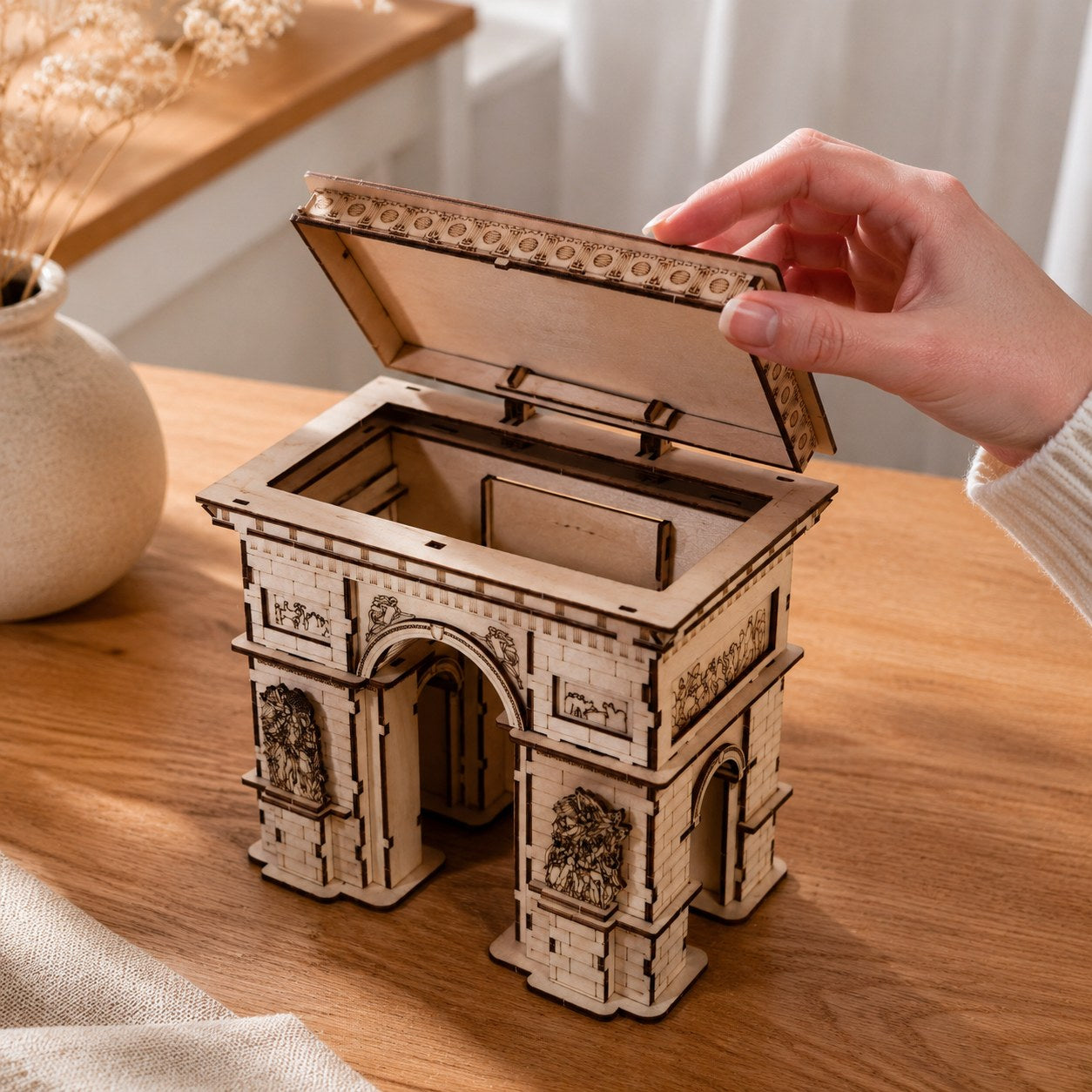 Hand opening the hidden storage compartment of the Arc de Triomphe model