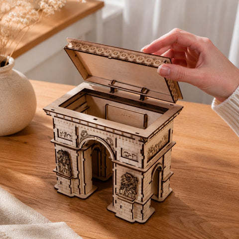 Hand opening the hidden storage compartment of the Arc de Triomphe model