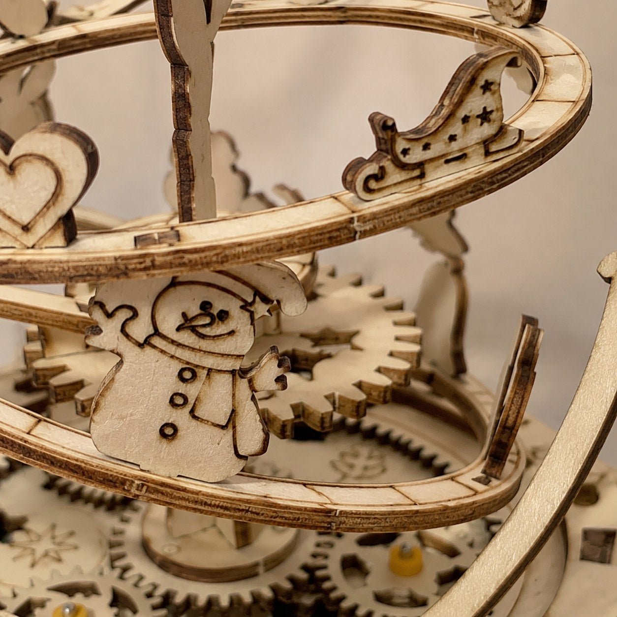 Macro close-up of laser-cut wooden gears and winter motifs on the Jigden music box