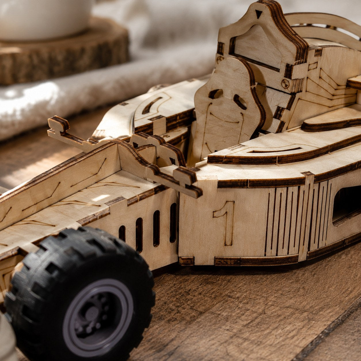 Extreme close-up of the laser-cut wood grain, interlocking joints, and rubber tire tread on the race car model.