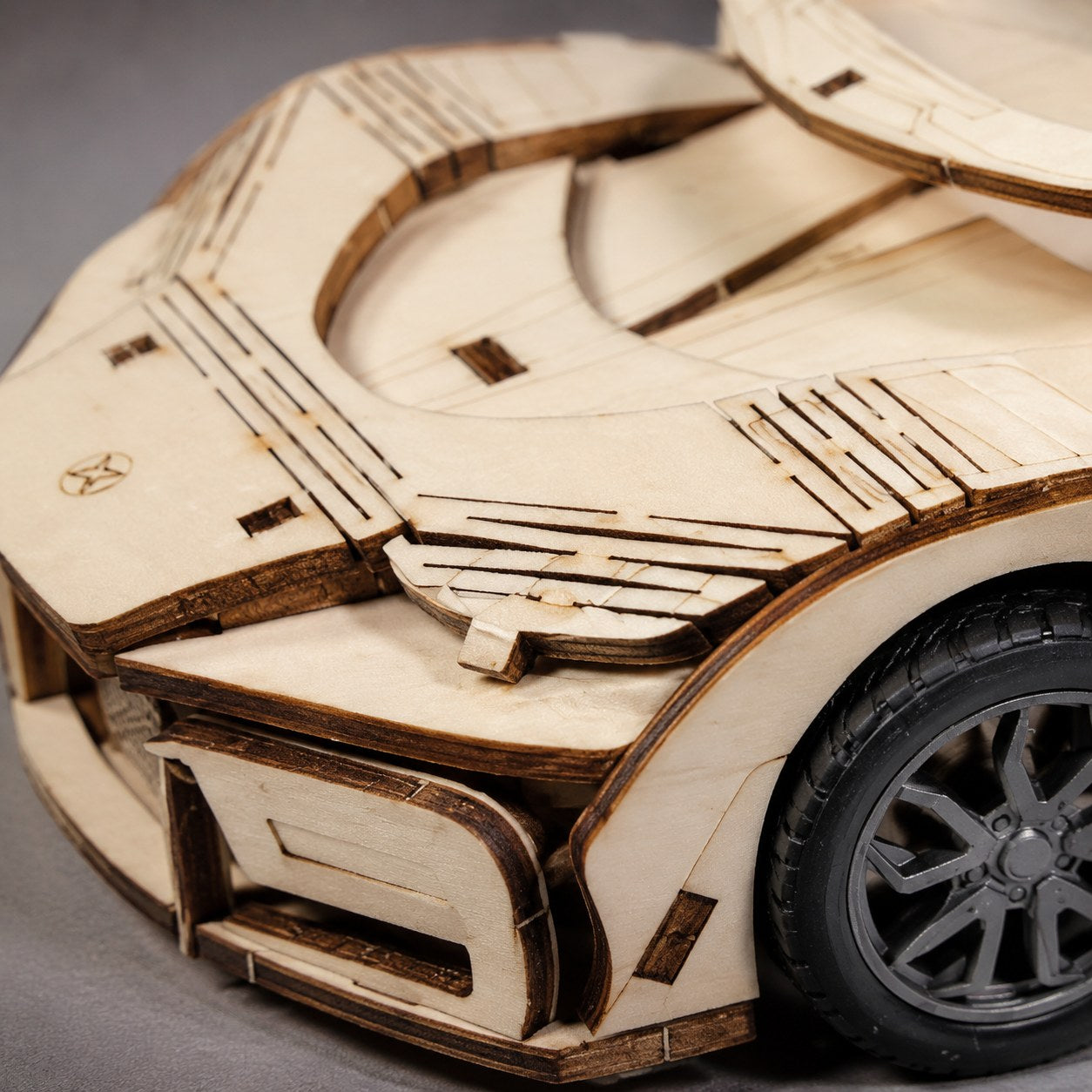 Macro close-up of the laser-cut wood details and tire on the Jigden hypercar model