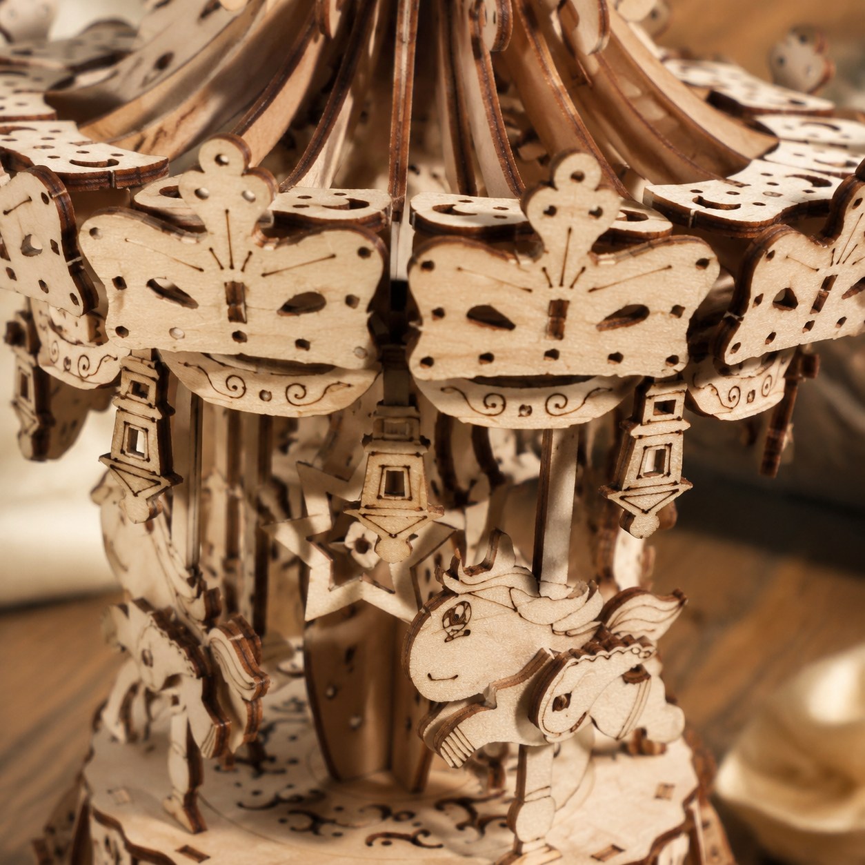 Macro close-up of the laser-cut details on the wooden carousel canopy and horses
