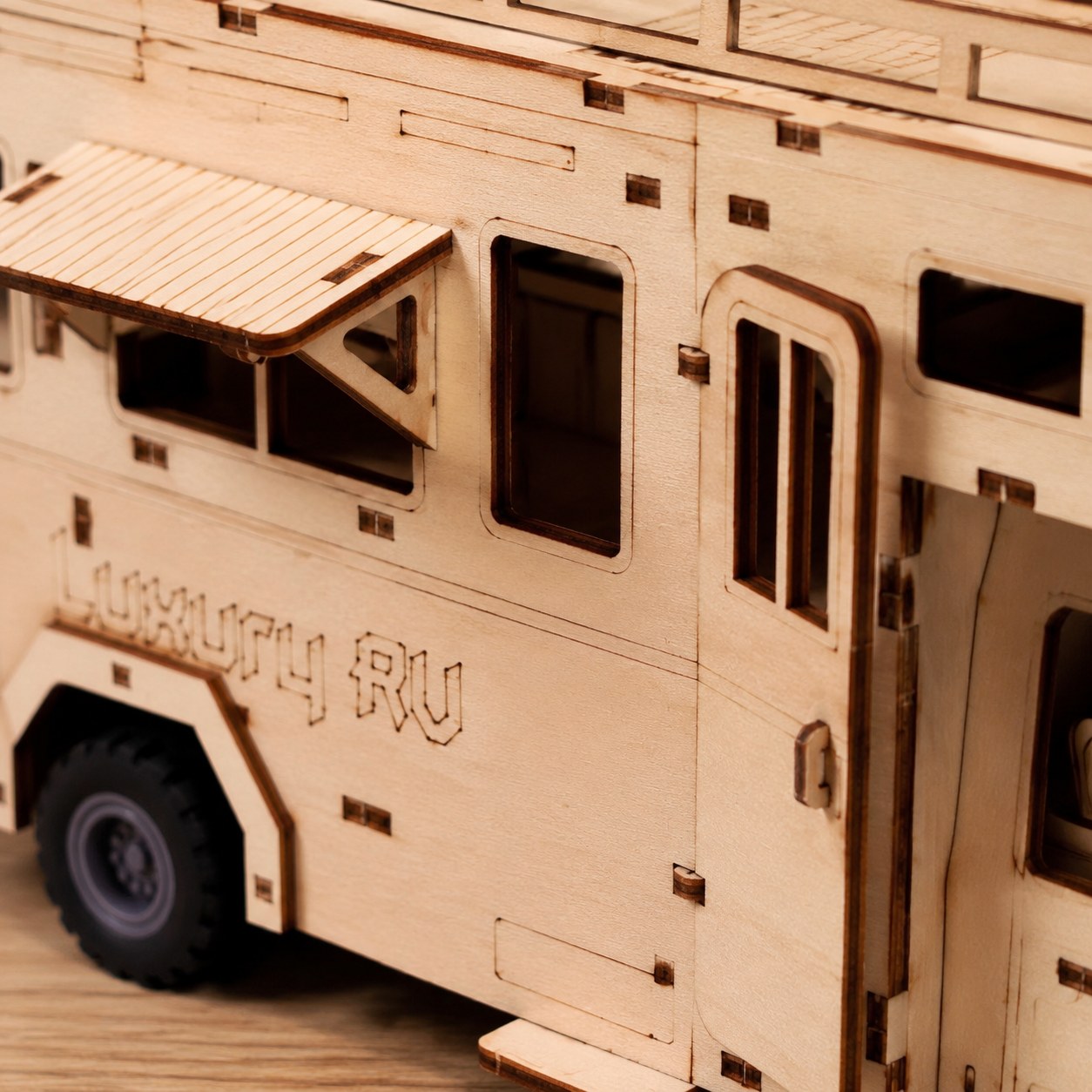 Macro close-up showing laser-cut wood details and engraving on the RV camper model
