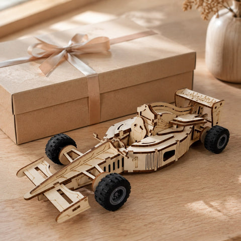 Finished wooden race car model displayed next to a minimalist gift box on a cream surface.