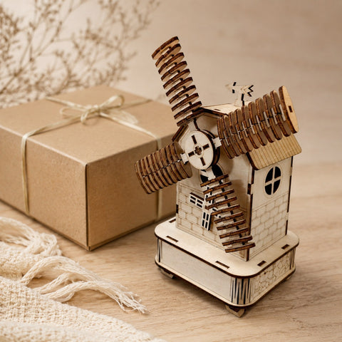 Finished wooden windmill music box displayed next to a wrapped gift box